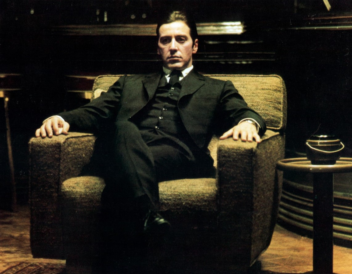 michael corleone sitting down wearing a three piece suit